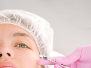 Close-up of a beautician administering facial injection treatment to a woman in a clinical setting.