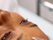 Close-up image of a cosmetic procedure showing a needle injecting into a forehead.