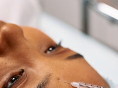 Close-up image of a cosmetic procedure showing a needle injecting into a forehead.