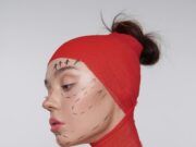 Artistic portrait showing cosmetic surgery markings on model in red wrap.