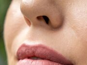 Minimal Lip Work: 2026’s Trend is Texture, Not Volume a close up of a woman's lips with a green background